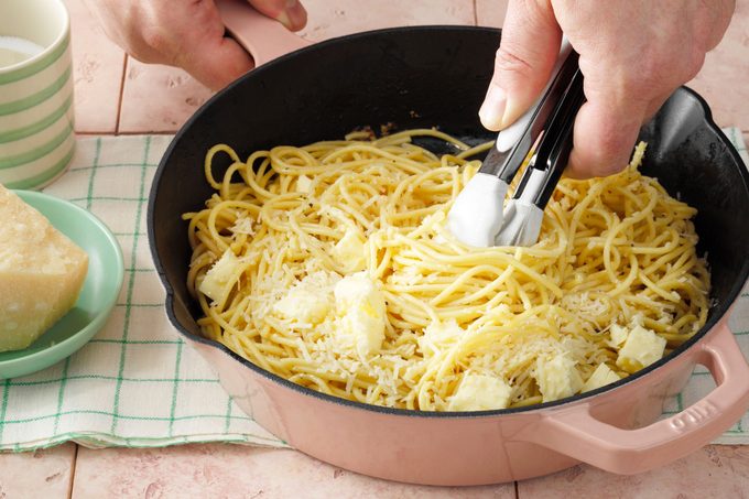 Showing cheese and butter added and someone stirring it (with hands).