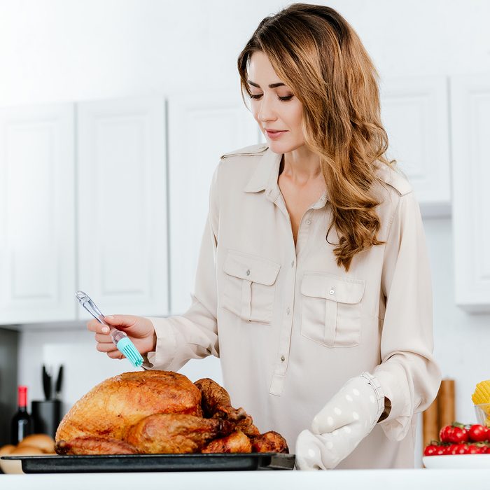 beautiful happy woman cooking thanksgiving turkey at kitchen