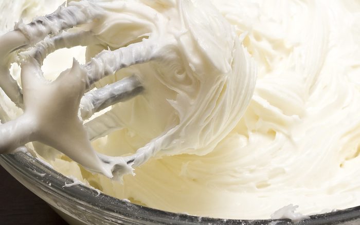 close up of cream cheese frosting mixed up in a glass bowl