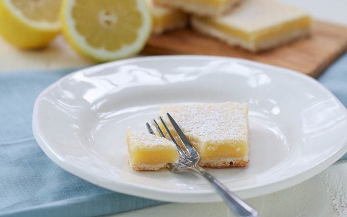 Single lemon bar on a plate with a fork