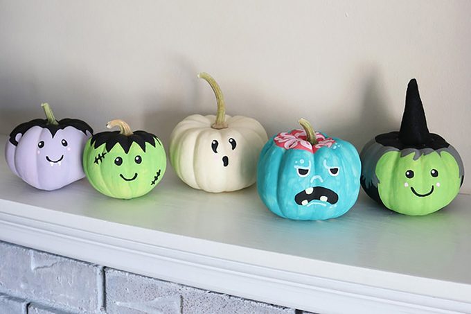 small Monster Painted Pumpkins in green, purple and white on a mantel in a house