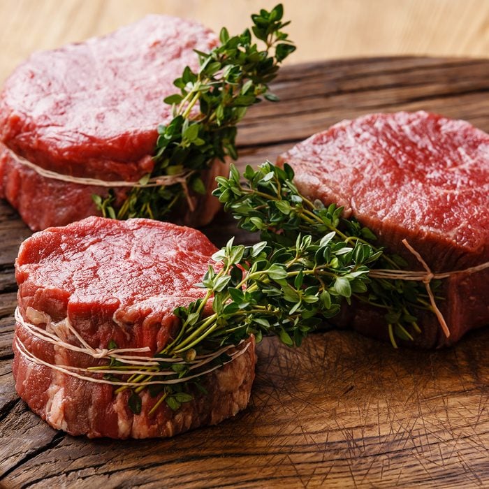 raw fresh filet mignon steaks with herbs on wood board