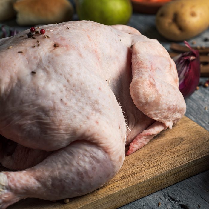 closeup of a rustic wooden table full of ingredients to prepare a stuffed turkey, such as a raw turkey, apple, onion, potato, carrot and different spices; Shutterstock ID 1223612134; Job (TFH, TOH, RD, BNB, CWM, CM): TOH