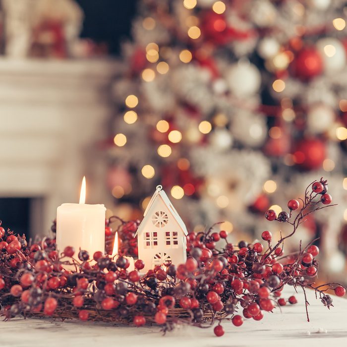 Candles and Christmas decoration on table over blurred evening lights background;