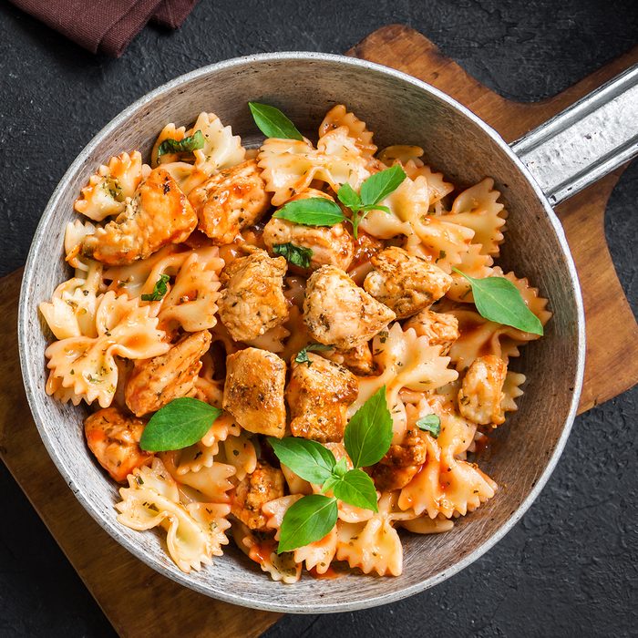 Farfalle pasta in tomato sauce with chicken, basil in pan. Chicken italian bow tie pasta over black background with copy space, homemade italian food.; Shutterstock ID 1241007715; Job (TFH, TOH, RD, BNB, CWM, CM): Taste of Home