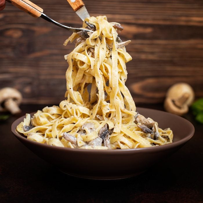 Homemade Italian fettuccine pasta with mushrooms and cream sauce (Fettuccine al Funghi Porcini). Traditional Italian cuisine. Served on a dark table with a rustic wooden background. Close-up; Shutterstock ID 1448882672; Job (TFH, TOH, RD, BNB, CWM, CM): Taste of Home