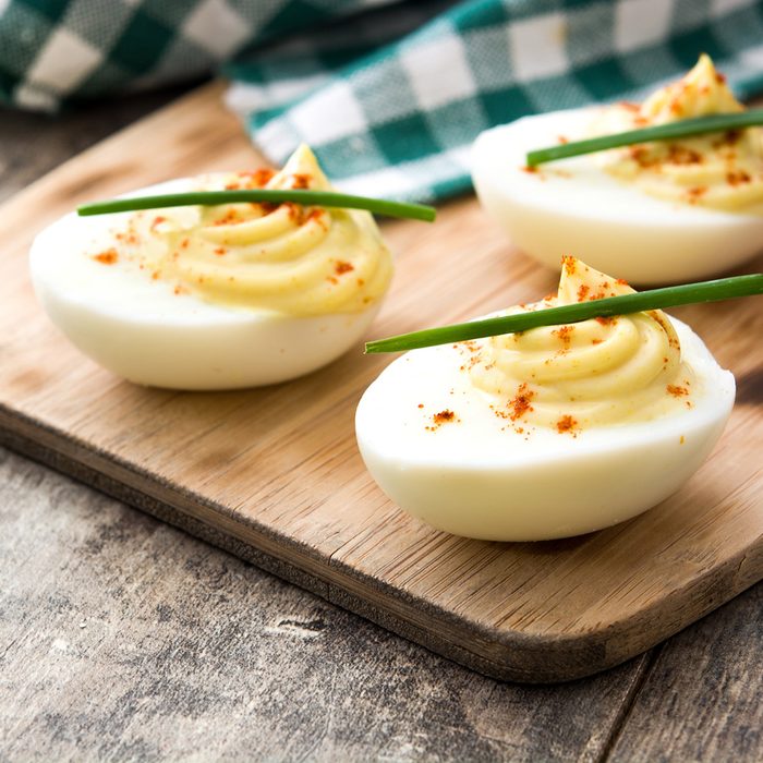 Stuffed eggs with mustard, mayo and paprika on wooden table