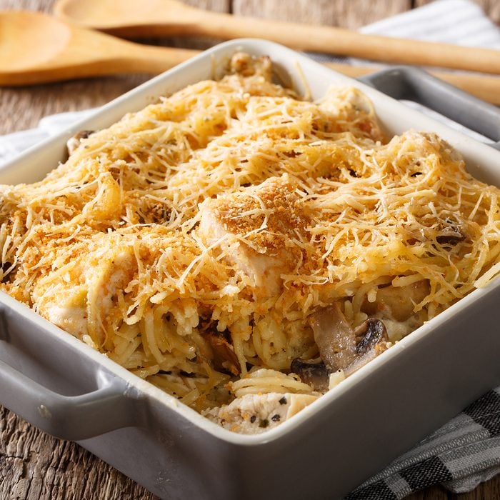 American tetrazzini with spaghetti, mushrooms, cheese, chicken close-up in a plate for baking on a table.