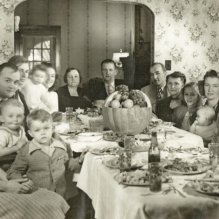 a very large family sitting around the table during thanksgiving dinner, looking at the camera, 1930s