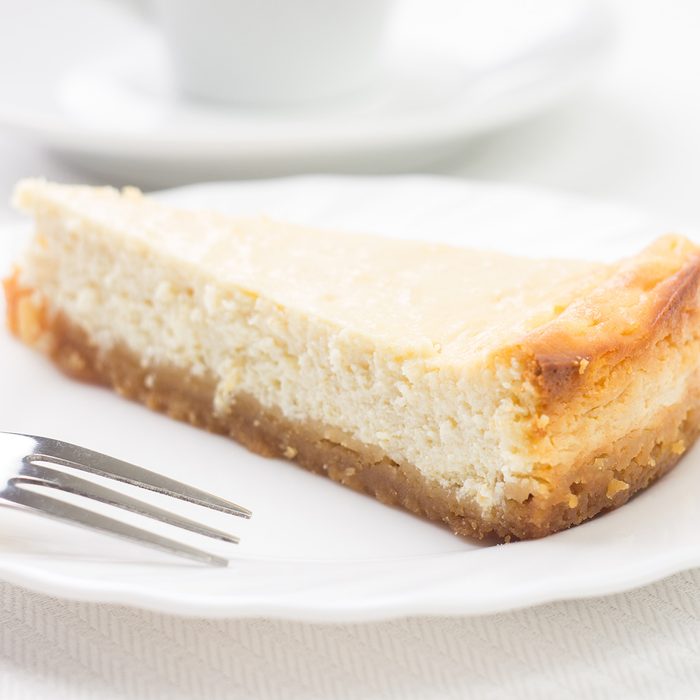 Piece of cheesecake on white plate with dessert fork. Menu recipe background