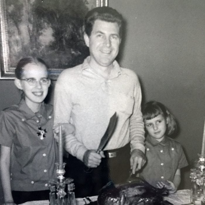 Father and daughters prepare to carve the turkey