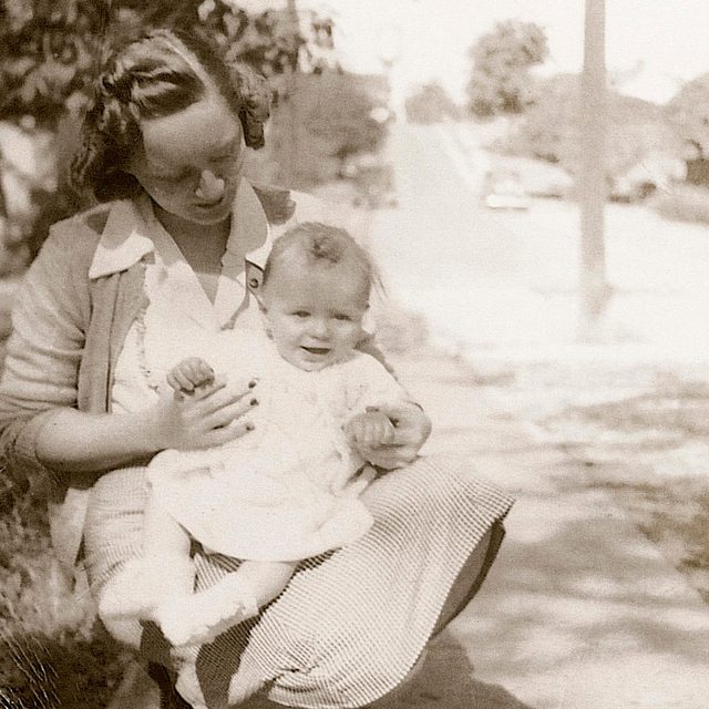 1930s mother crouched down holding her baby