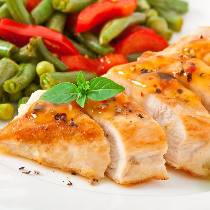 Chicken breast with vegetables and sauce decorated with basil leaves