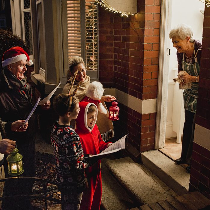 Three generation family are doing door-to-door carol singing. There is a senior woman at the door, appreciating their singing.; Shutterstock ID 672017293; Job (TFH, TOH, RD, BNB, CWM, CM): Taste of Home