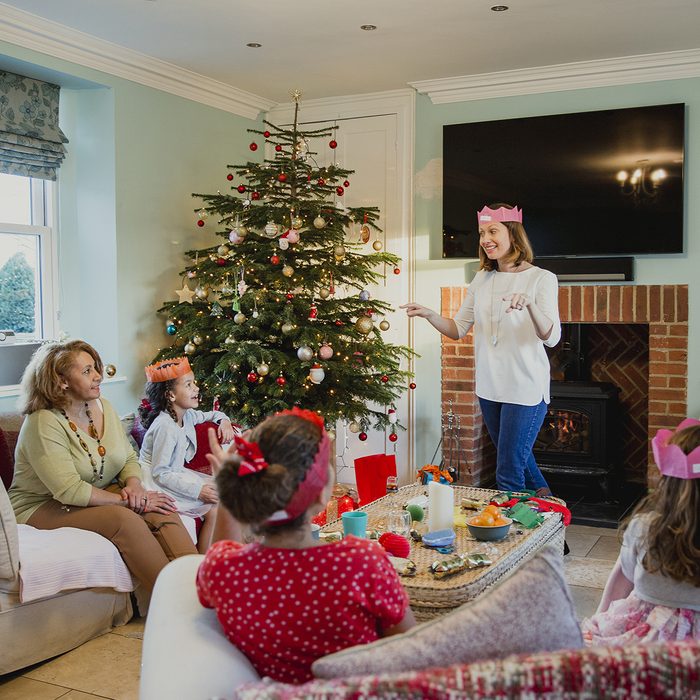 Family are playing charades at christmas time in the living room of their home. It's the mother's turn and everyone is trying to guess. ; Shutterstock ID 723224050; Job (TFH, TOH, RD, BNB, CWM, CM): Taste of Home