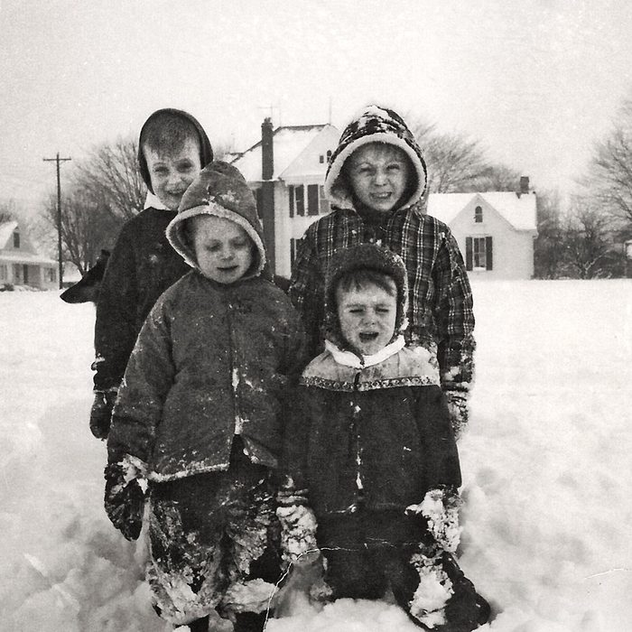 Black and white photo of four children kneeling in the snow