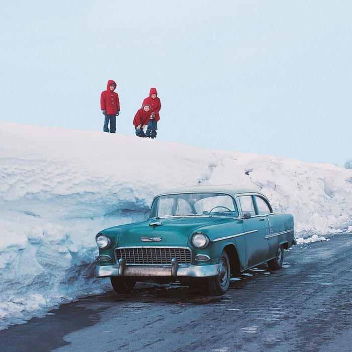 Children looking down at a car from a huge snow hill