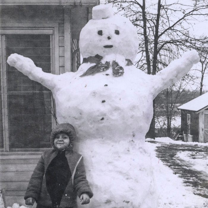 Child standing beside a giant snowman