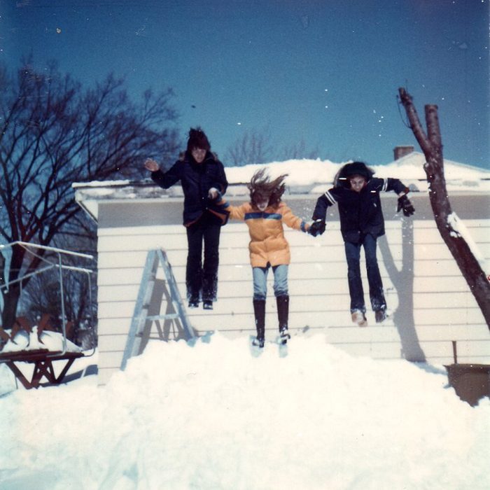 Three people jumping off a roof and into a snow bank
