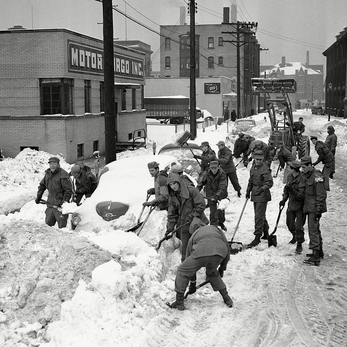 members of the Ohio National Guard help clear the streets, shoveling snow away from totally engulfed cars