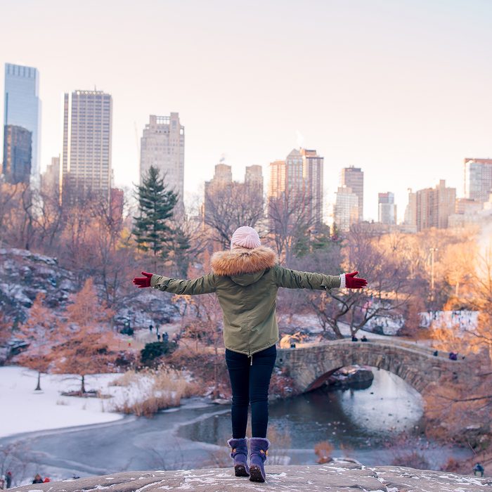 Back view of woman enjoy the view of ice-rink in Central Park and skyscrapers on Manhattan in New York City