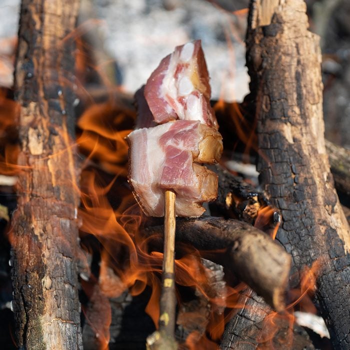 bacon baking spit on fire barbecue camping in the nature stock photo