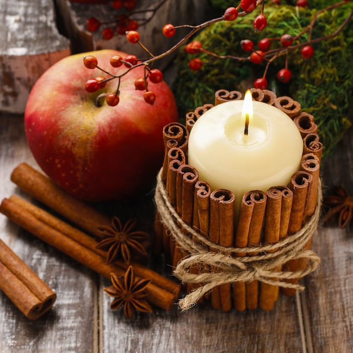 Candle decorated with cinnamon sticks and red apples, christmas decoration