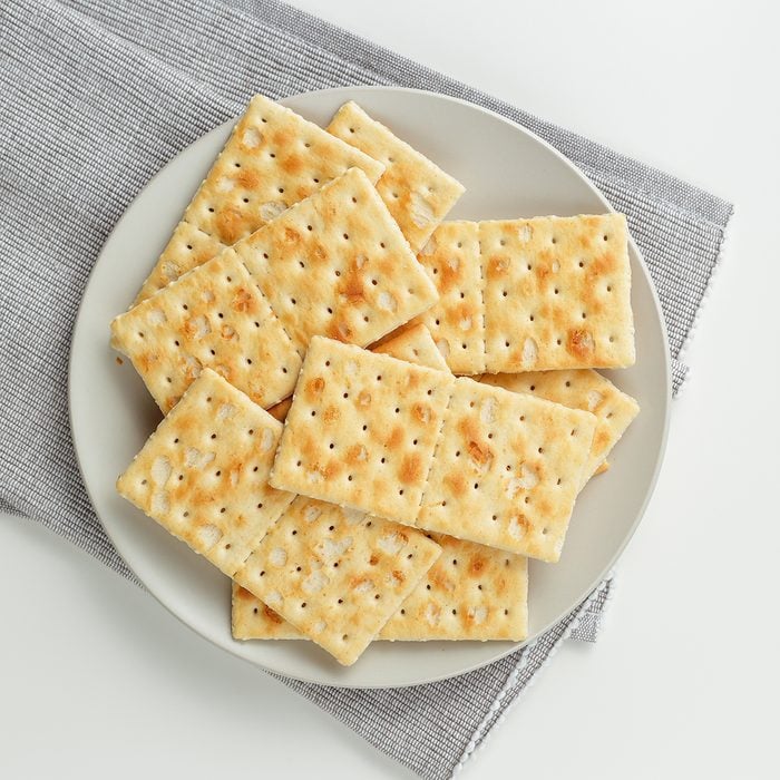 Closeup of a snack plate. Stack of crackers on grey plate and grey napkin over white background