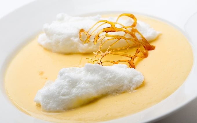 Floating islands, fluffy poached meringue on a lake of custard made from egg yolks, milk, sugar and vanilla, topped with a caramel framework. This is a traditional French farmhouse dessert.