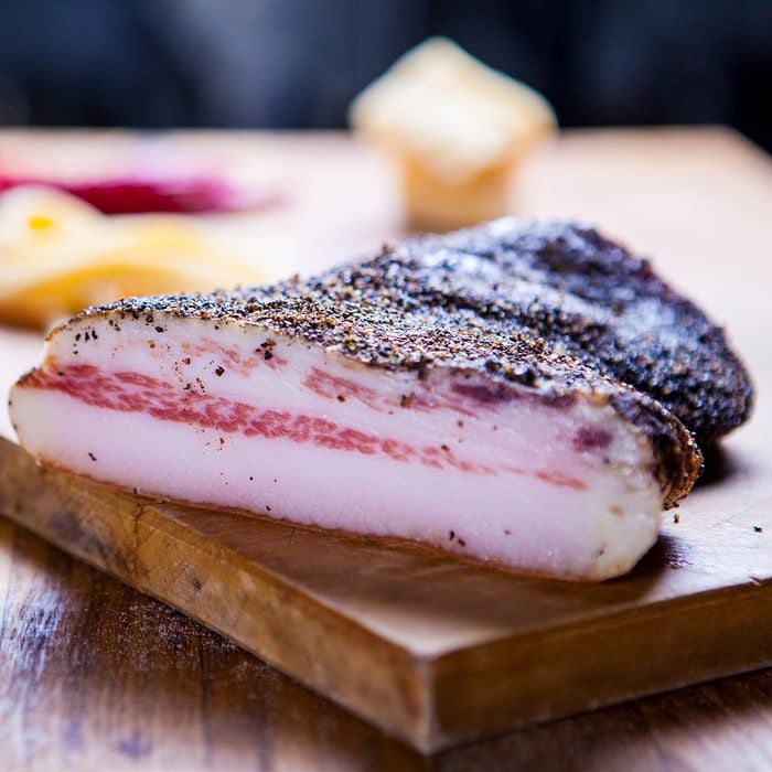 Guanciale, cured meat product prepared from pork jowl, Italian Food .Section of a Rustic Italian Bacon on wooden plate. 