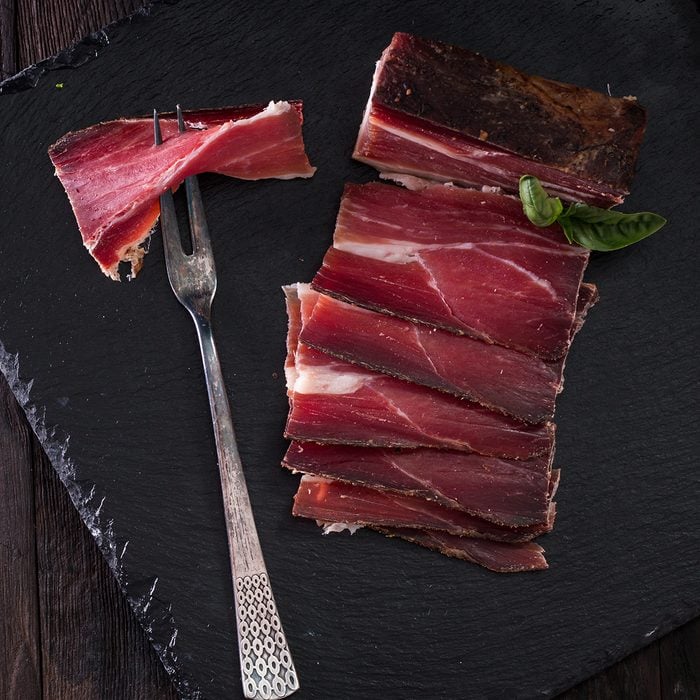 italian Speck, delicious ham on vintage background