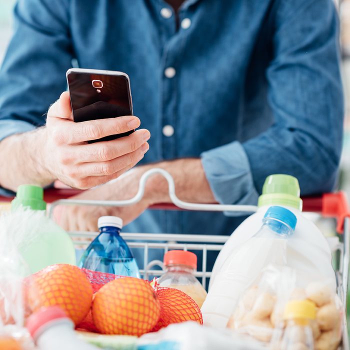 Man shopping at the supermarket, he is leaning in the shopping cart and connecting with his mobile phone; Shutterstock ID 617768495; Job (TFH, TOH, RD, BNB, CWM, CM): TOH