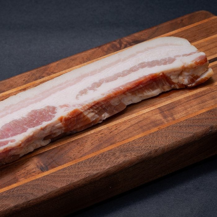 Rashers of Uncured Apple Smoked Bacon arranged on natural wooden cutting board.