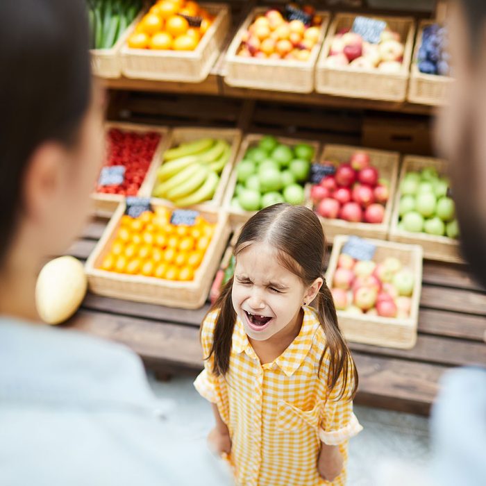 Upset hysterical girl with closed eyes crying loudly while manipulating parents and standing against food stall in supermarket; Shutterstock ID 1220942938; Job (TFH, TOH, RD, BNB, CWM, CM): TOH