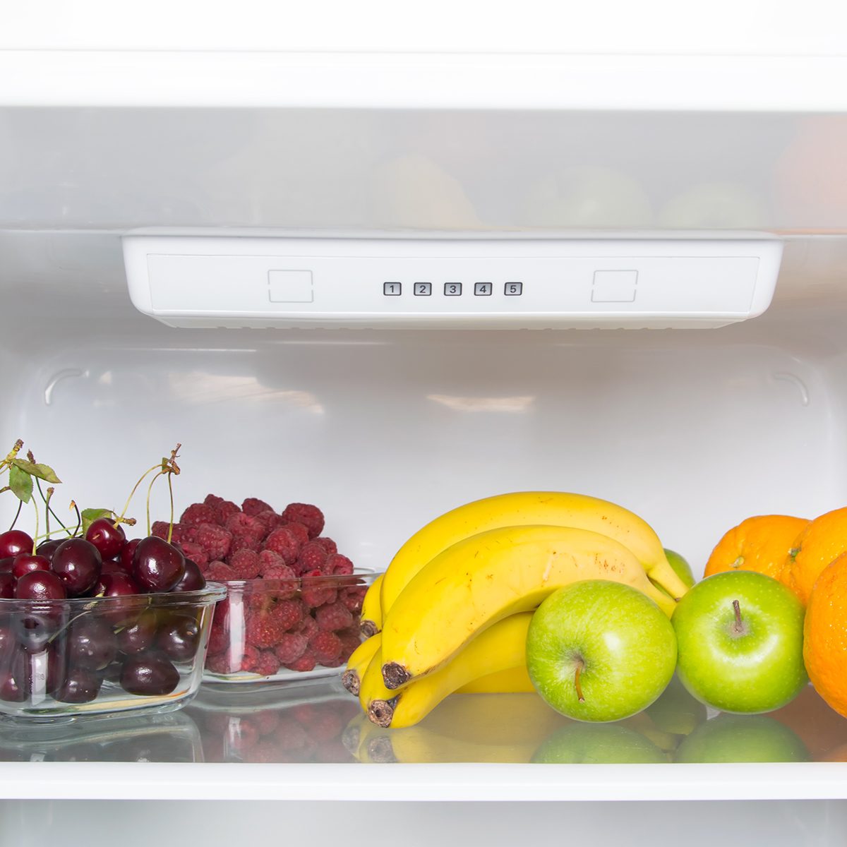 White refrigerator shelf close-up, fruits and berries, raspberries and cherries