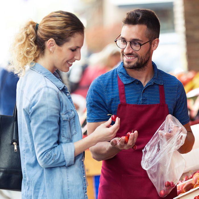 Shot of salesman helping customer to choose some types of fruits