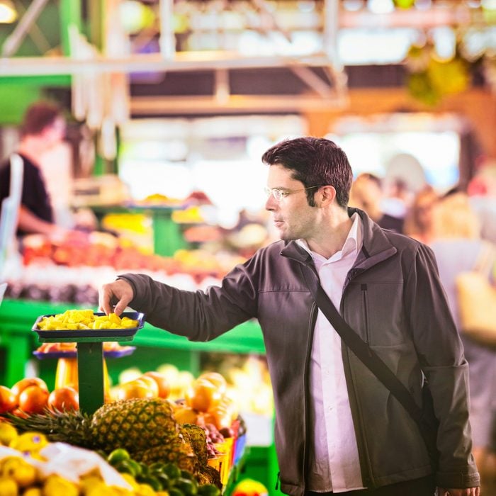 Handsome man sampling pineapples at the market.