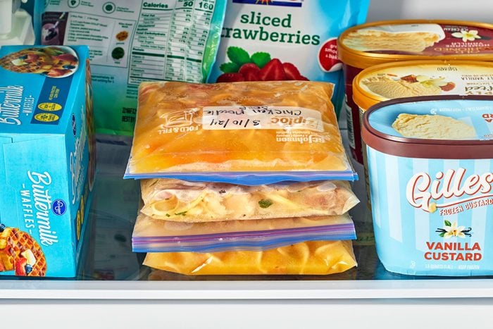 Stack of three flat freezer bags with frozen soup in a freezer