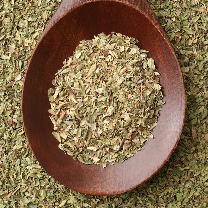 Top view of wooden spoon full of dried oregano