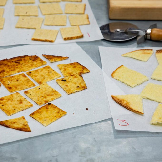 three parchment sheets of cut up cauliflower crusts