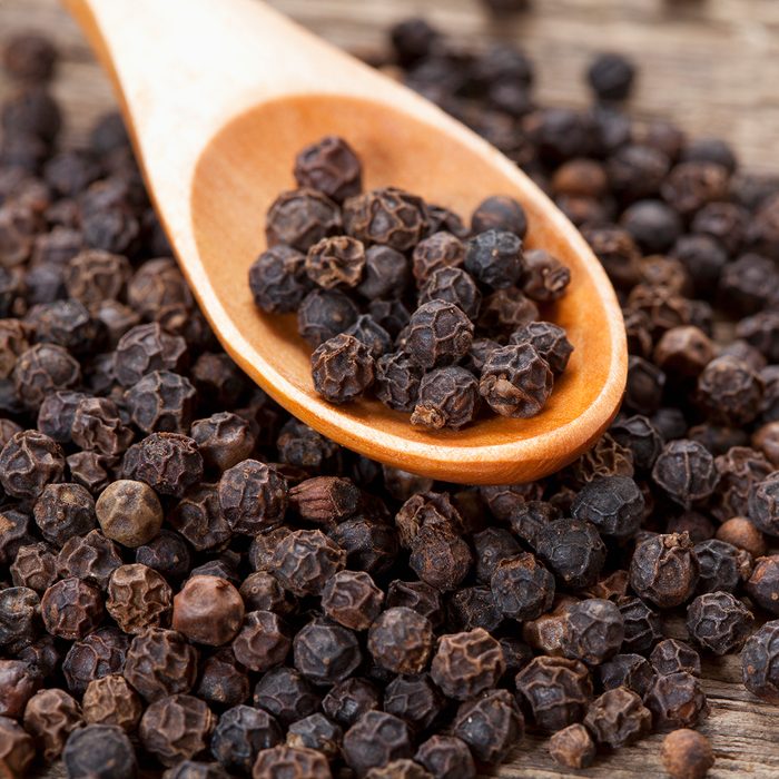 close up of black peppercorn in wooden teaspoon