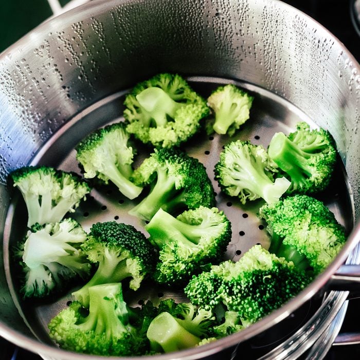 Broccoli florets being cooked in a steamer.