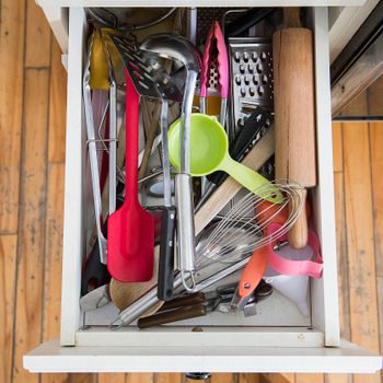 a kitchen drawer packed with utensils is shown