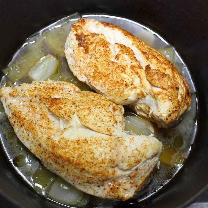 Delicious braised chicken breast cooked in a Dutch oven resting on the stove top in a home kitchen.