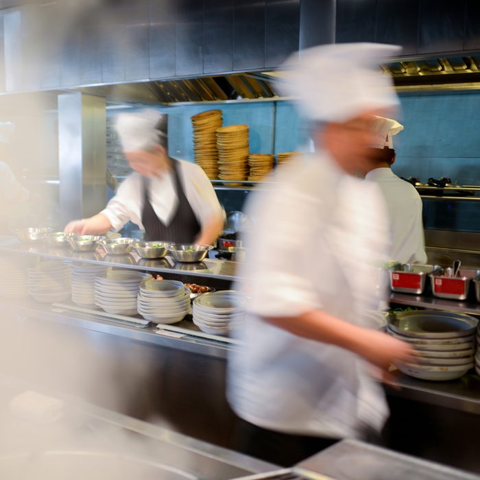 Many busy chefs are working in a big restaurant kitchen