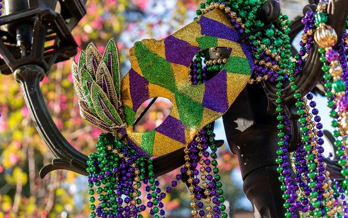 Outdoor Mardi Gras beads and mask on light post in sunshine
