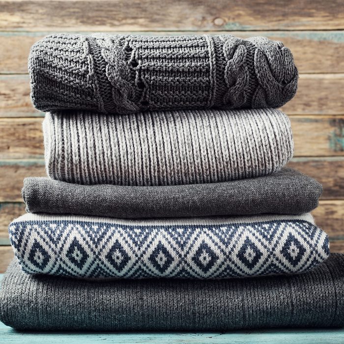 Pile of knitted winter clothes on wooden background, sweaters, knitwear