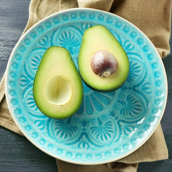 Sliced avocado on plate, on wooden background