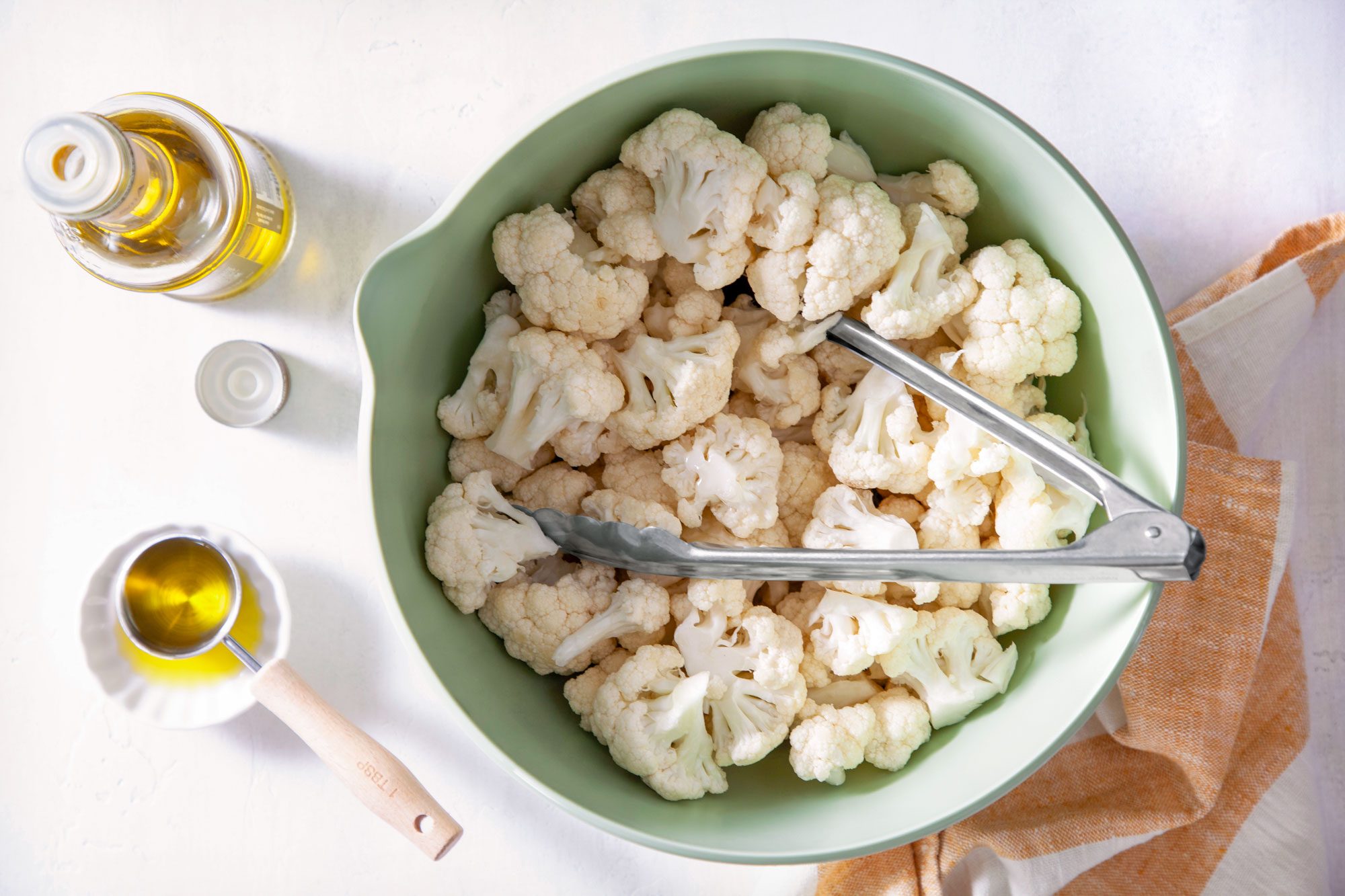 Cauliflower in a Big Bowl with Oil in a Bottle and A Spoon