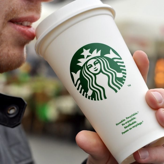 Warsaw, Poland - April 8, 2016: An Unidentified man holding a cup of beverage from Starbucks cafe in Warsaw